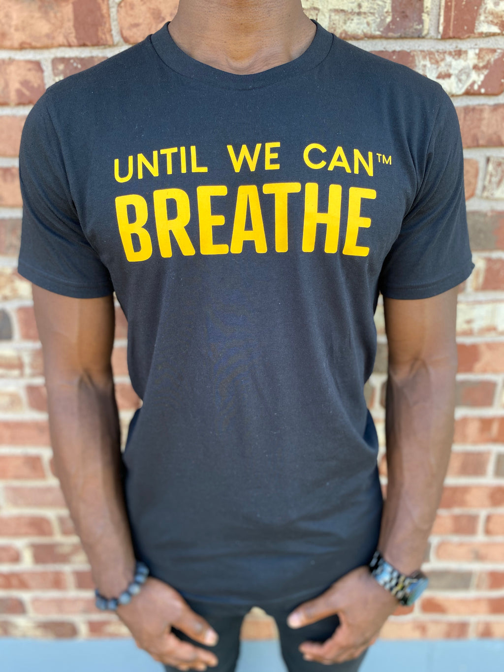Short sleeve black t-shirt with yellow gold "Until We Can Breathe" texts, in support of Black Lives Matter, racial justice, and black pride. Remembering the last works of Eric Garner, George Floyd, and many others. Made by black woman owned business and environmentally friendly.
